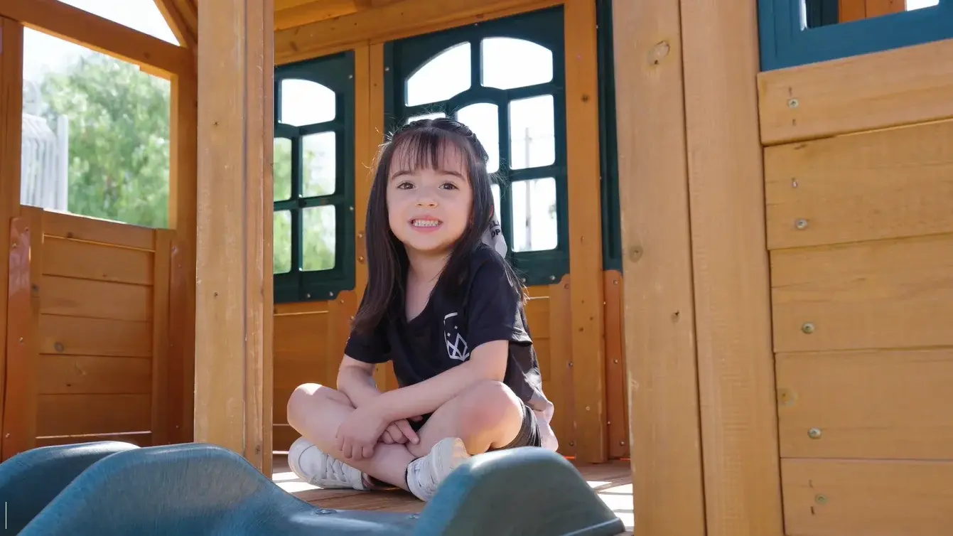 Estudiante sonriendo dentro de una estructura de madera con ventanales, en ambiente educativo natural